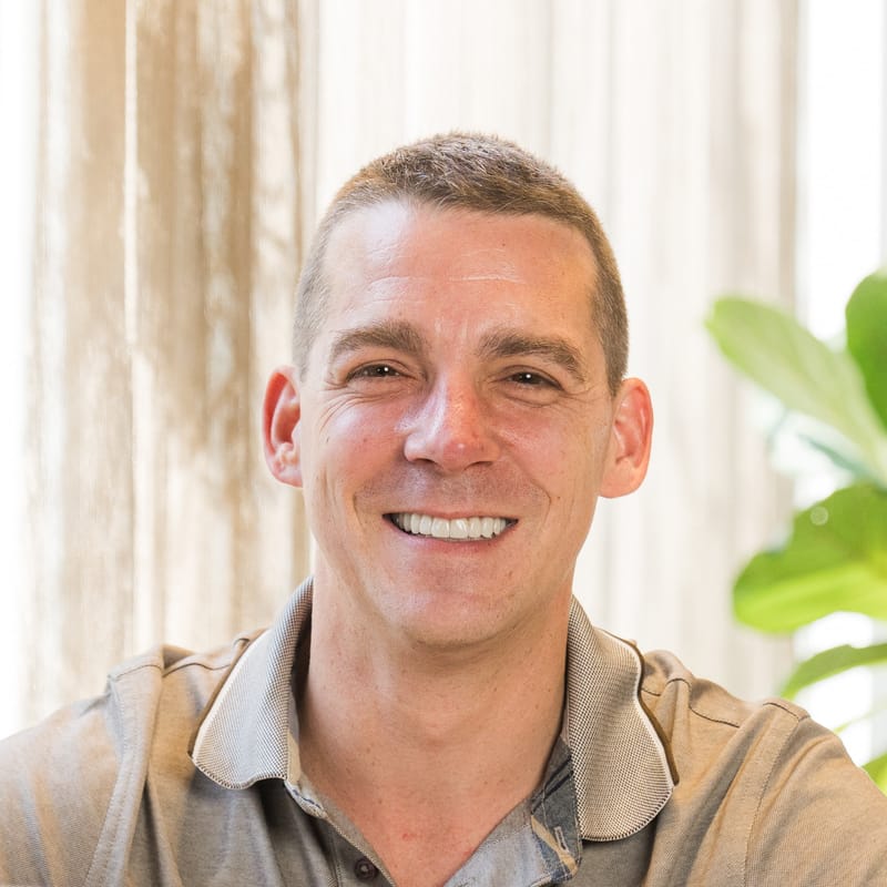 Bert Neels, oprichter en web developer van BusinessBoosters, lachend achter zijn laptop op kantoor in Lommel